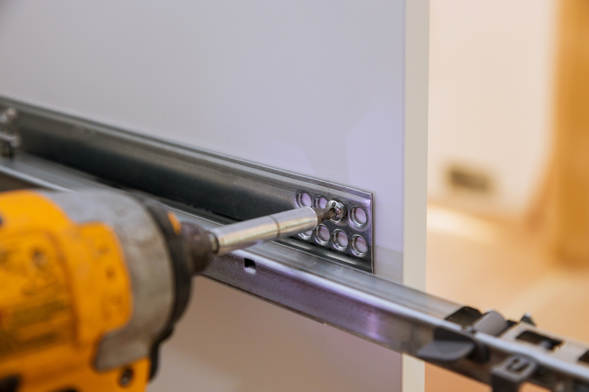 Handyman fitting a cabinet hinge during property maintenance